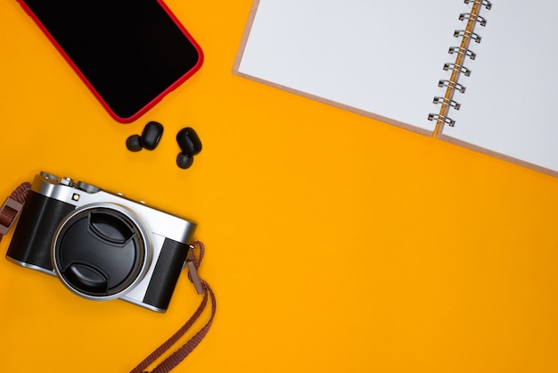 Travel concept with camera note and smartphone on orange background