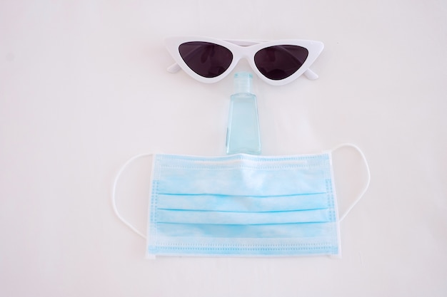 Travel under Covid-19 and new normal concepts. medical face mask, hand gel sanitizer and sunglasses on white bed, prevent coronavirus or Corona Virus Disease