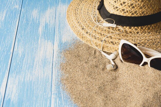 Travel equipment, eyeglasses and sun hat on blue wooden background.