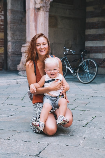 Viaggia in europa. la famiglia sorridente felice dei turisti trascorre del tempo nel centro storico di verona, italia. madre e figlio stanno viaggiando e camminando in una città europea.