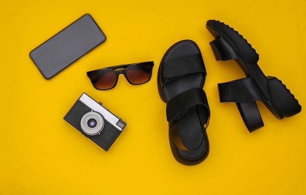 Travel flat barking. Sandals, sunglasses, camera and smartphone on a yellow background. Top view