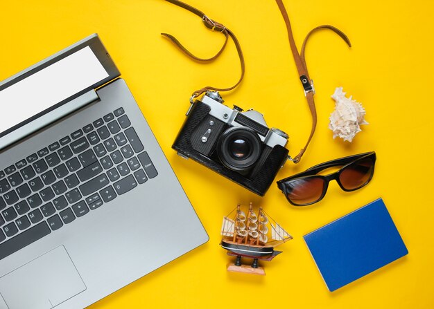 Accessori da viaggio piatti laici e fotocamera retrò su giallo