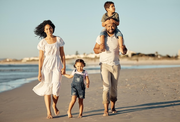 Travel freedom and happy family at the beach walking and bonding on ocean trip together Portrait of loving parents enjoying fun getaway with their children caring and playing on a walk at sunset