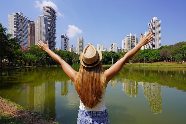 Travel in Goiania Brazil Back view of girl with raising arms in the city park Vaca Brava in Goiania Goias Brazil