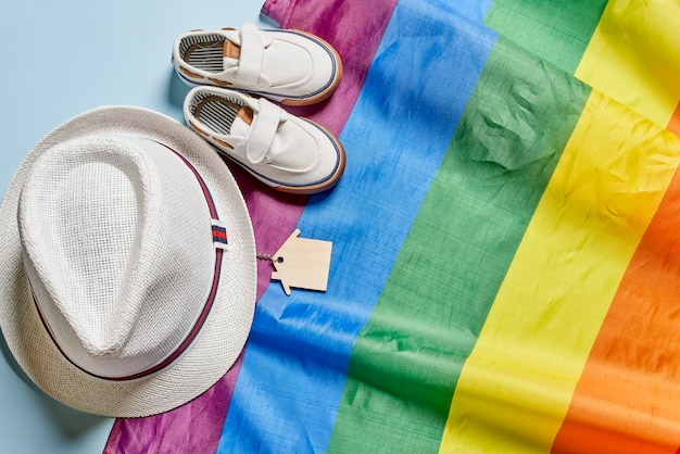 Foto cappello da viaggio scarpe estive e chiavi di casa sulla bandiera arcobaleno lbgtq