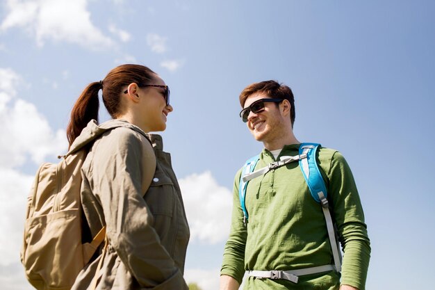 旅行、ハイキング、バックパッキング、観光、人々 のコンセプト - 屋外で話しているバックパックと幸せなカップル