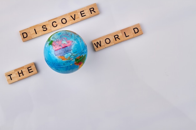 Travel holiday concept. Alphabet wooden cubes and globe on white background. Discover the world made from letter blocks.