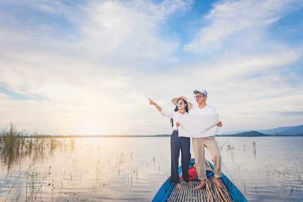 湖と山の眺めを持つボートの尾に立っているMapkを持つ旅行の男と女、Travel conc