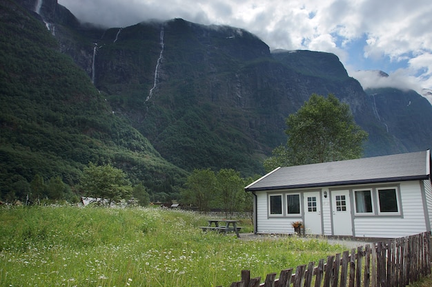 노르웨이로 여행하면 높은 산 근처의 공터에 작은 집이 있습니다.