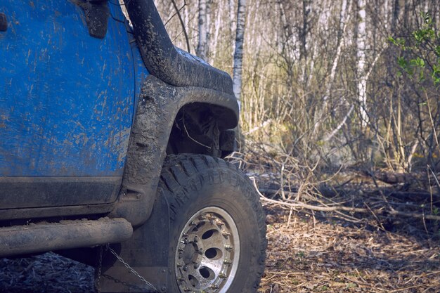 Travel off-road on a forest road in a blue 4x4 car. The 4x4 SUV is all dirty