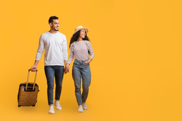 Travel Offer Smiling Arab Couple Walking With Suitcase And Looking Aside