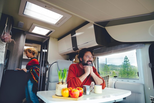 Travel people and off grid lifestyle living van life inside a\
camper happy serene couple enjoy van life with modern rv vehicle\
nature outdoors outside the window view man and woman indoor