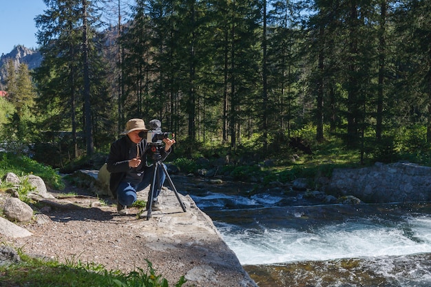 写真 森の三脚にカメラを持つ旅行カメラマン男、舞台裏を撮影