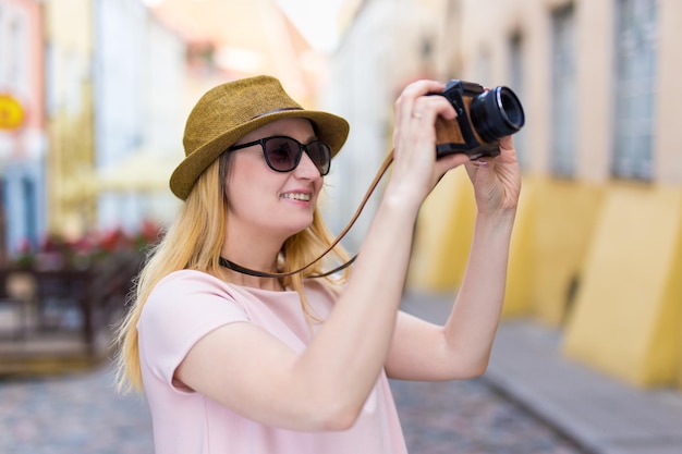 Travel and photography concept - young woman tourist taking photos with retro camera