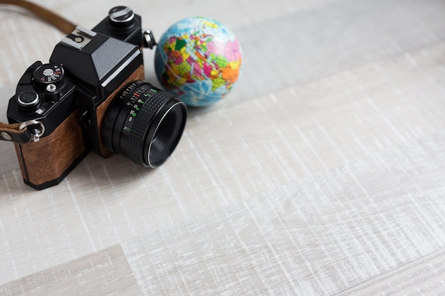 Винтажная камера путешествия и фотографии и маленький глобус на деревянном фоне с копией пространства