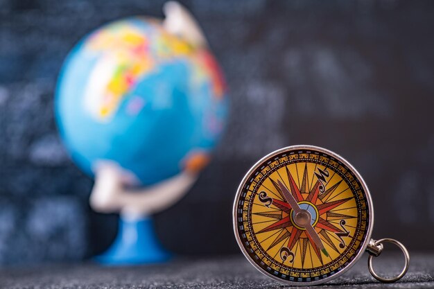 Photo travel planning navigation concept classic magnetic detail of compass on light blue with earth globe in the backround