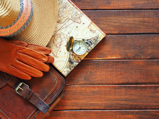 Travel planning Old compass map straw hat leahter briefcase and gloves on wooden background