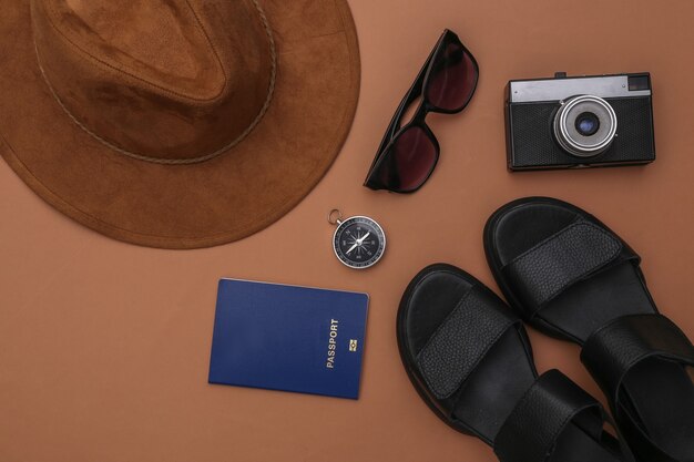 Photo travel planning. sandals, hat and travel accessories on brown background. top view. flat lay