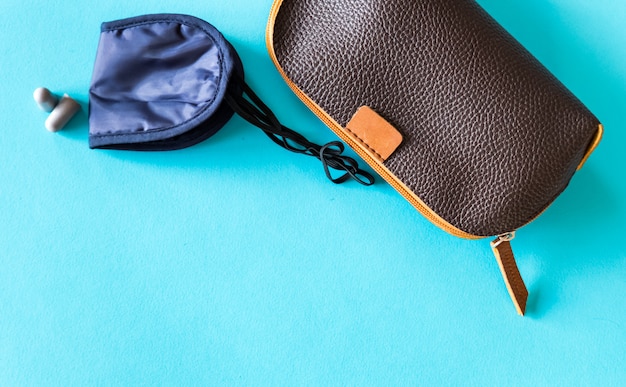 Travel size cosmetic set, eye mask and ear plugs on blue background.