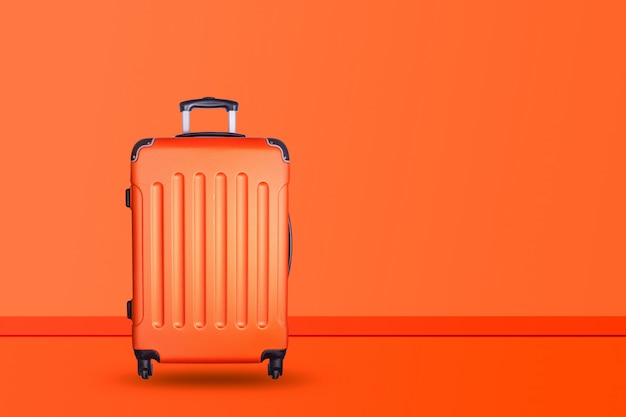 Travel suitcase on orange background