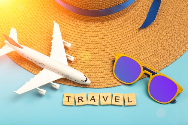 Travel summer background. Sunglasses, hat, airplane and beach accessories on a colored blue background. Tourist vacation, relaxation and summer concept. High quality photo