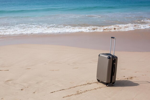 Travel on summer and tourist planning with yellow suitcase with\
yellow hat fashion in the beautiful beach travel in holiday blue\
sky and sand background on travel in summer concept