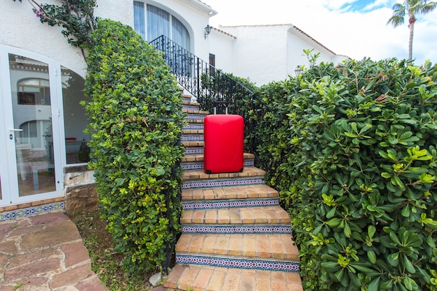 Travel, tourism and accessory concept - a red suitcase standing on stair over the nature surface.