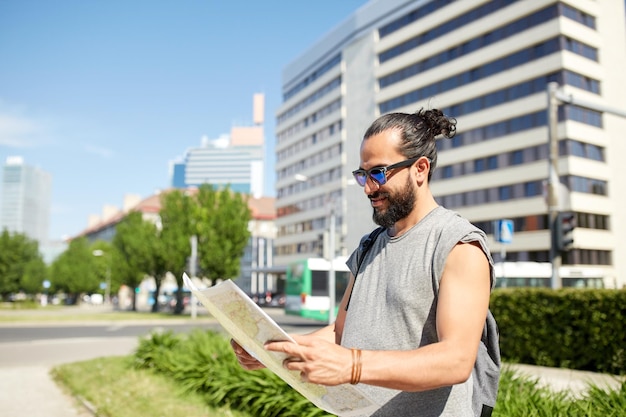 travel, tourism, backpacking and people concept - man traveling with backpack and map in city searching location