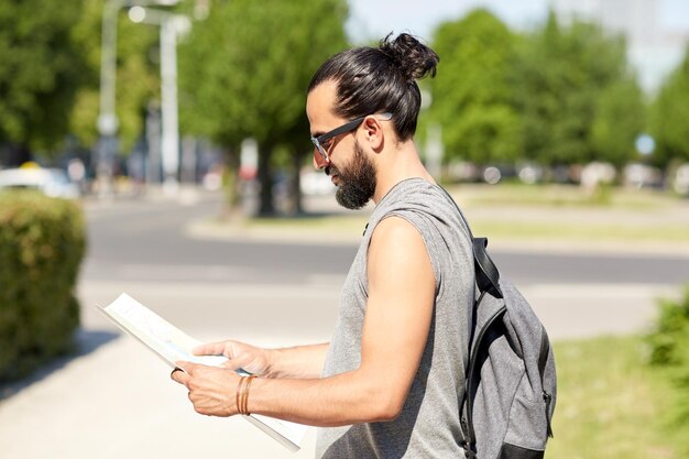 Photo travel, tourism, backpacking and people concept - man traveling with backpack and map in city searching location