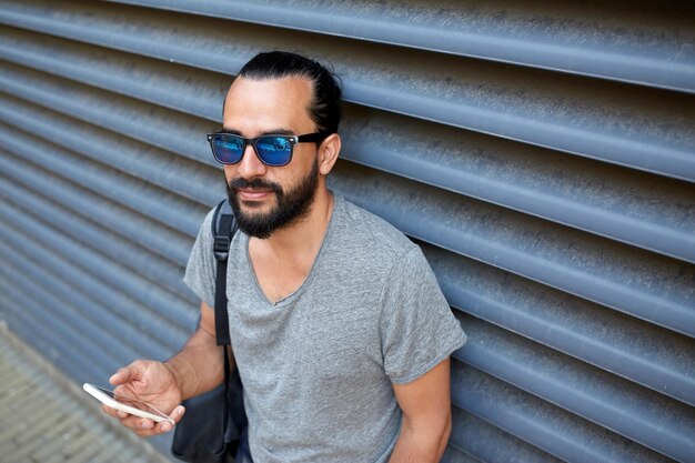 travel, tourism, communication, technology and people concept - man with backpack texting on smartphone on city street