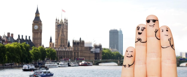 концепция путешествий, туризма, семьи, людей и частей тела - крупный план четырех пальцев со смайликами на фоне лондонского города