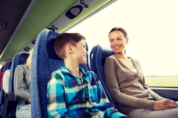Фото Концепция путешествий, туризма, семьи, технологий и людей - счастливая мать и сын едут в туристическом автобусе
