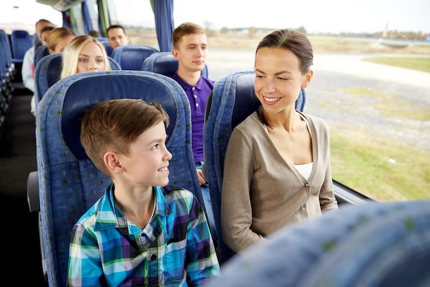 travel, tourism, family, technology and people concept - happy mother and son riding in travel bus