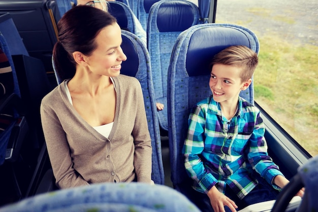 travel, tourism, family, technology and people concept - happy mother and son riding in travel bus