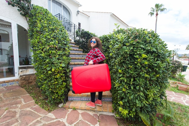 Travel, tourism and journey concept. happy young woman climbing up the stairs with red suitcase and smiling.