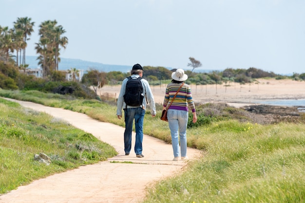 Viaggi e turismo. coppie mature della famiglia che godono della vista che cammina insieme lungo la spiaggia, vista dalla parte posteriore