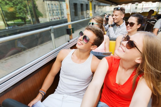 Concetto di viaggio, turismo, vacanze estive, visite turistiche e persone - gruppo di amici adolescenti sorridenti in occhiali da sole che viaggiano in autobus turistico