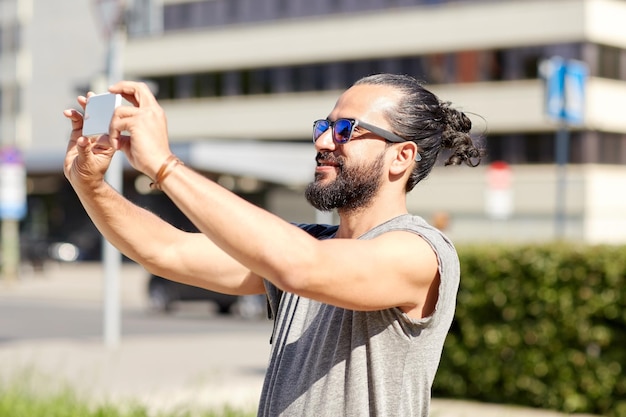 旅行、観光、技術、人のコンセプト – 夏の街でスマートフォンでビデオや自撮りをする笑顔の男性