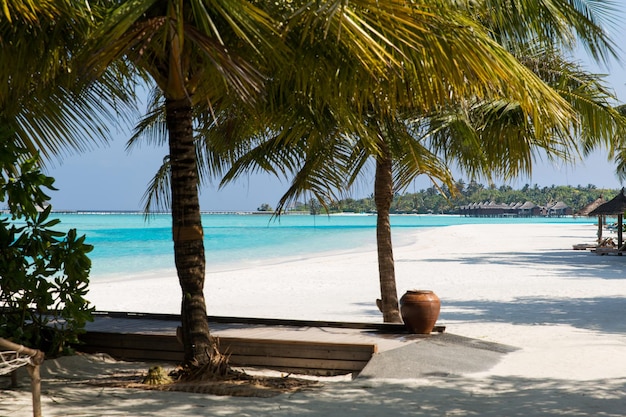 travel, tourism, vacation and summer holidays concept - bungalow huts in sea water on exotic resort beach