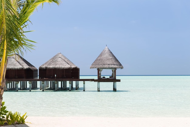 travel, tourism, vacation and summer holidays concept - bungalow huts in sea water on exotic resort beach