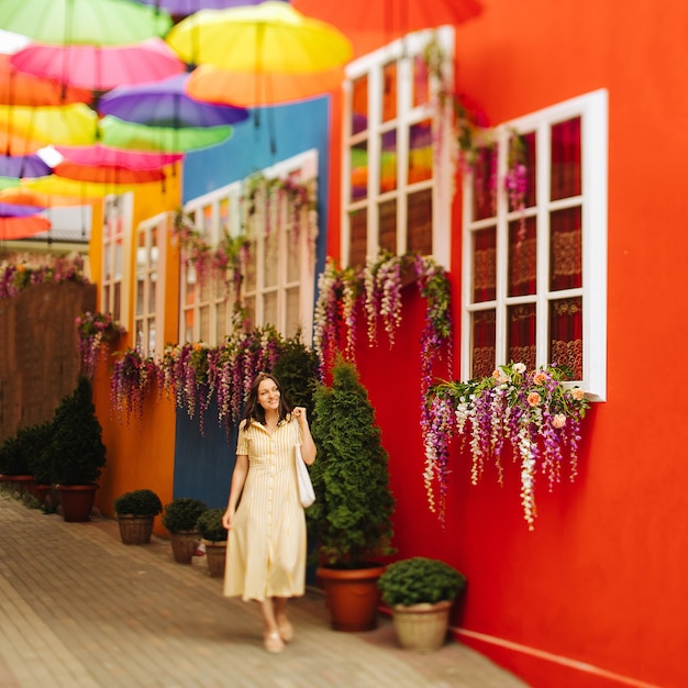 Travel tourist brunette woman in yellow dress walks the streets with bright decoration of the city.  Tilt-shift lens blur