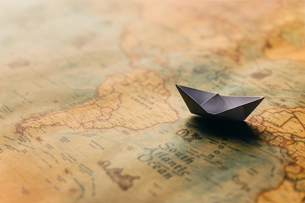 Travel and transportation concept White paper ship on geographical map background