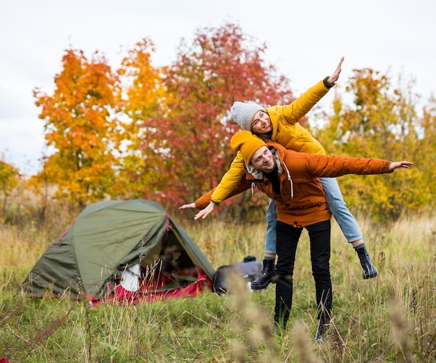 travel trekking and hiking concept portrait of couple in love having fun near tent in autumn forest