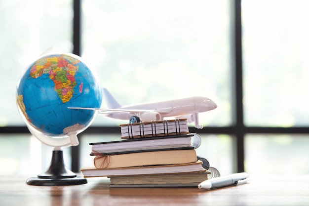 Travel , trip vacation, close up of toy airplane, pen and note pad and globe on wooden table