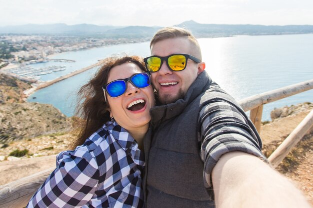 Foto viaggio, vacanza e concetto di vacanza - belle coppie che si divertono, prendendo selfie, facce emotive pazze e ridendo.