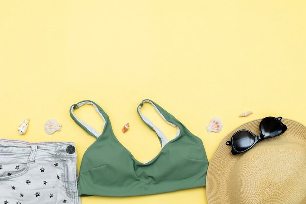 Travel vacation summer flat lay accessories objects hat sunglasses clothes bathing suit seashells on yellow background with copy space planning trip adventure