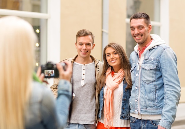 travel, vacation, technology and friendship concept - girl picturing group of friends in city