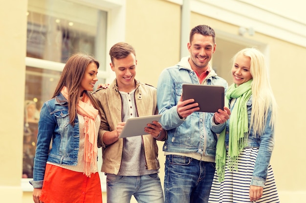 travel, vacation, technology and friendship concept - group of smiling friends with tablet pc computers in the city