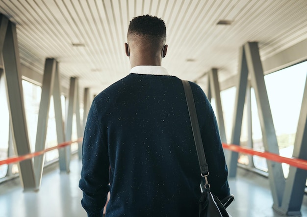 Foto visione di viaggio e uomo d'affari nero che fa un viaggio per una riunione o un seminario di networking globale vista posteriore dell'imprenditore all'aeroporto giovane professionista in missione per migliorare le competenze e raggiungere obiettivi di carriera