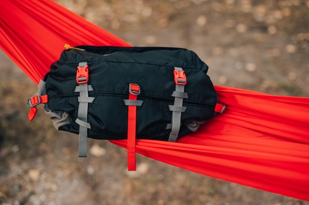 여행용 허리 가방은 숲속의 빨간 해먹에 놓여 있습니다. 허리 가방 광고 사진